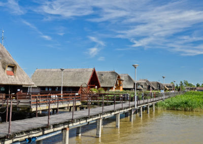 Houses on legs behind a long pier on a lake
